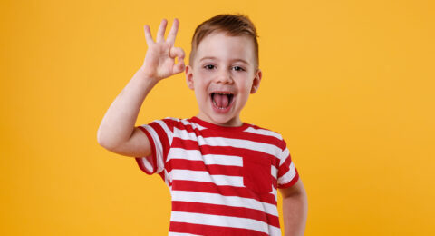 Excited little boy standing and showing okay gesture