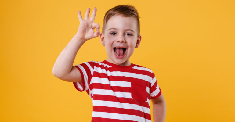 Excited little boy standing and showing okay gesture